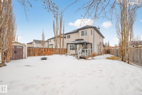 Snow covered rear of property featuring a gazebo, a fire pit, a chimney, a fenced backyard, and a wooden deck - 152 Rue Marquet, Beaumont, AB - Outdoor
