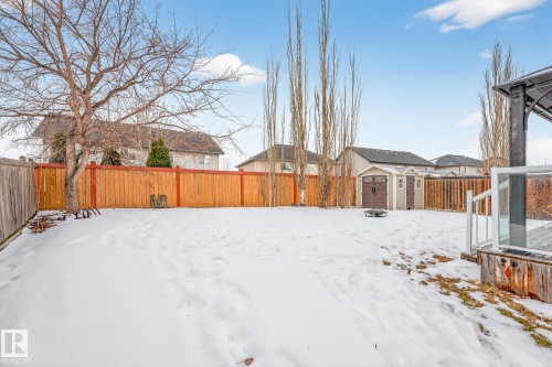 Yard covered in snow with a fenced backyard and a storage unit - 152 Rue Marquet, Beaumont, AB - Outdoor