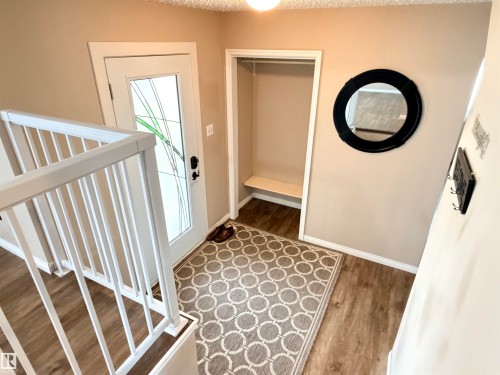 Entryway featuring wood-finish flooring, a full-lite door with decorative glass, and a built-in storage alcove with a bench - 10503 110 Street, Westlock, AB 
