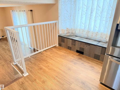 Wood-finish flooring, white railing, built-in window seating, and stainless steel appliance - 10503 110 Street, Westlock, AB 