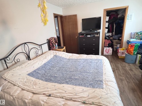 Bedroom with wood finished floors, a textured ceiling, and a walk in closet - 10503 110 Street, Westlock, AB 