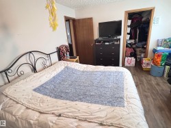 Bedroom with wood finished floors, a textured ceiling, and a walk in closet - 