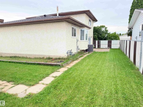 Expansive side yard featuring a manicured lawn, concrete paver pathway, and chain-link fencing - 10503 110 Street, Westlock, AB 