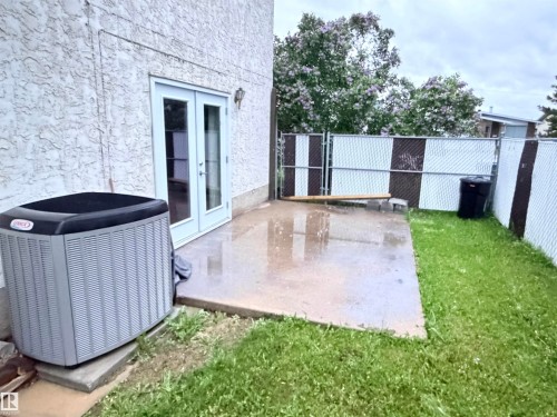 Private patio area featuring a concrete slab, exterior wall sconce, and double glass doors - 10503 110 Street, Westlock, AB 