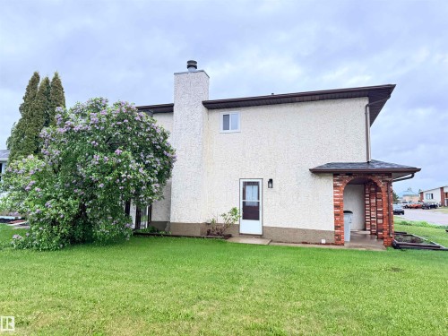 Stucco exterior with a prominent chimney and a mature flowering tree - 10503 110 Street, Westlock, AB 