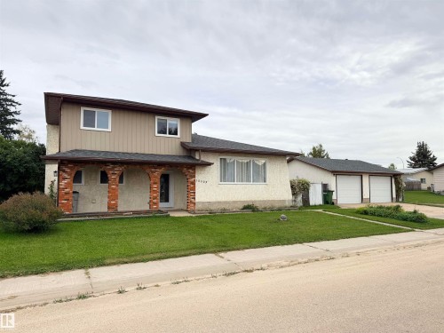 Two-story residence with brick archway detailing, a light-colored stucco finish, and a two-car garage with white doors - 10503 110 Street, Westlock, AB 