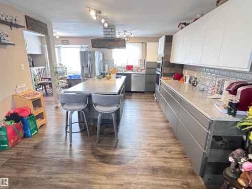 Kitchen featuring light countertops, stainless steel appliances, a kitchen island, exhaust hood, and two tone color scheme - 10503 110 Street, Westlock, AB 