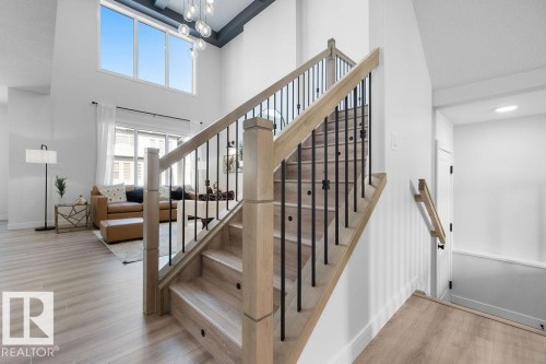 Stairs featuring wood finished floors, a high ceiling, and hanging lights - 3722 41 Avenue, Beaumont, AB - Indoor Photo Showing Other Room