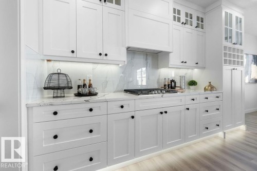 Kitchen with light stone counters, glass fronted cabinets, white cabinets, and tasteful backsplash - 3722 41 Avenue, Beaumont, AB - Indoor Photo Showing Kitchen