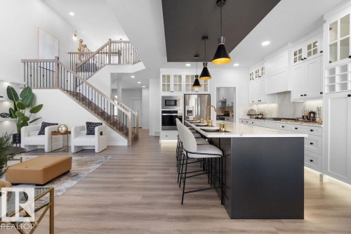 Dual tone kitchen featuring a kitchen breakfast bar, two tone cabinets, an island with sink, decorative light fixtures, and stainless steel appliances - 3722 41 Avenue, Beaumont, AB - Indoor Photo Showing Kitchen With Upgraded Kitchen