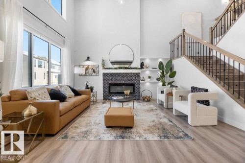 Living room featuring a tiled fireplace, light wood-style flooring, a high ceiling, and built in features - 3722 41 Avenue, Beaumont, AB - Indoor Photo Showing Living Room With Fireplace