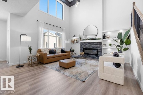 Living area featuring a tile fireplace, a high ceiling, and light wood-type flooring - 3722 41 Avenue, Beaumont, AB - Indoor Photo Showing Living Room With Fireplace