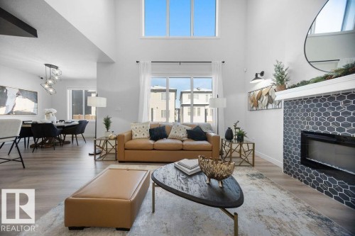 Living room featuring a glass covered fireplace, wood finished floors, and a high ceiling - 3722 41 Avenue, Beaumont, AB - Indoor Photo Showing Living Room With Fireplace