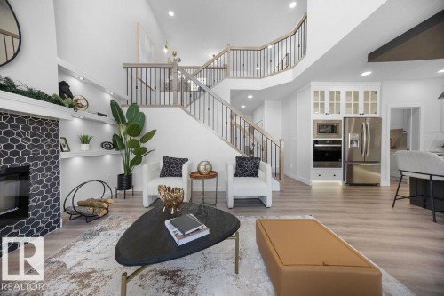 Living area featuring a glass covered fireplace, light wood-style flooring, recessed lighting, and a high ceiling - 3722 41 Avenue, Beaumont, AB - Indoor