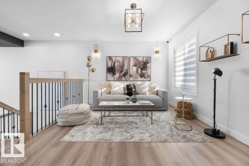 Sitting room featuring light wood-style floors, hanging lights, and an upstairs landing - 3722 41 Avenue, Beaumont, AB - Indoor Photo Showing Living Room