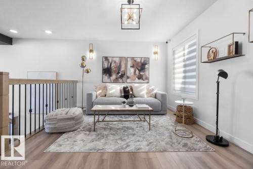 Living area with light wood-style floors and hanging lights - 3722 41 Avenue, Beaumont, AB - Indoor Photo Showing Living Room