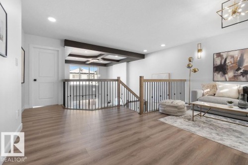 Living area with hanging lights, an upstairs landing, coffered ceiling, and wood finished floors - 3722 41 Avenue, Beaumont, AB - Indoor