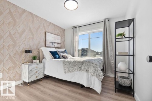 Bedroom featuring wallpapered walls, an accent wall, and light wood finished floors - 3722 41 Avenue, Beaumont, AB - Indoor Photo Showing Bedroom