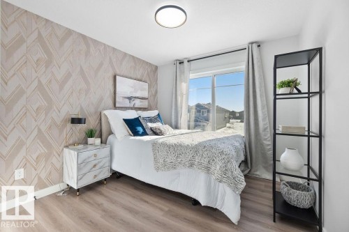 Bedroom with wallpapered walls, an accent wall, and light wood finished floors - 3722 41 Avenue, Beaumont, AB - Indoor Photo Showing Bedroom