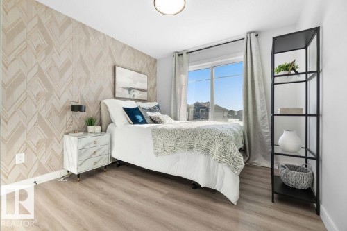 Bedroom with wallpapered walls, an accent wall, and light wood finished floors - 3722 41 Avenue, Beaumont, AB - Indoor Photo Showing Bedroom