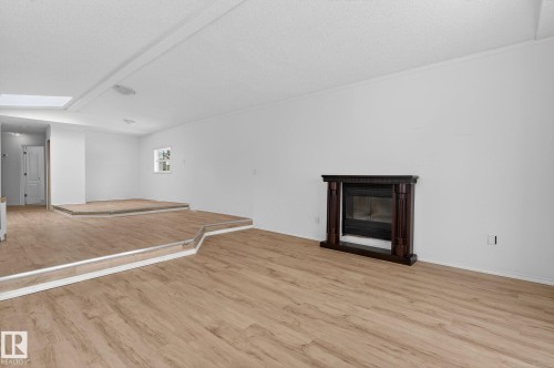 Unfurnished living room featuring a glass covered fireplace, light wood finished floors, and a skylight - 72 Evergreen Park, Edmonton, AB - Indoor With Fireplace