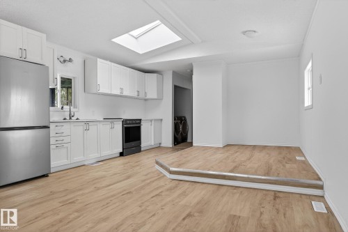 Kitchen featuring freestanding refrigerator, white cabinets, a skylight, range with electric cooktop, and light countertops - 72 Evergreen Park, Edmonton, AB - Indoor Photo Showing Kitchen