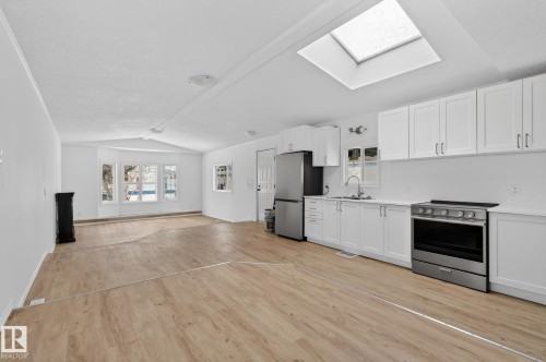 Kitchen with stainless steel appliances, white cabinets, light wood-style flooring, open floor plan, and healthy amount of natural light - 72 Evergreen Park, Edmonton, AB - Indoor Photo Showing Kitchen