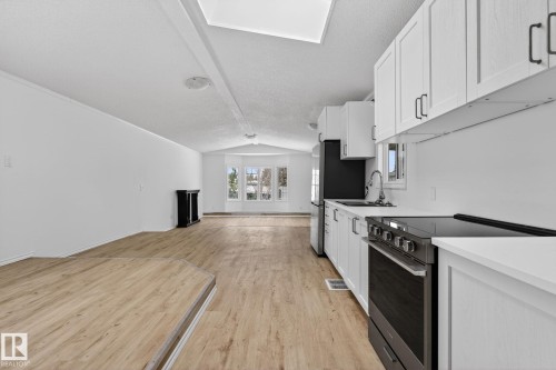 Kitchen with stainless steel appliances, white cabinets, light countertops, beam ceiling, and light wood-type flooring - 72 Evergreen Park, Edmonton, AB - Indoor Photo Showing Kitchen