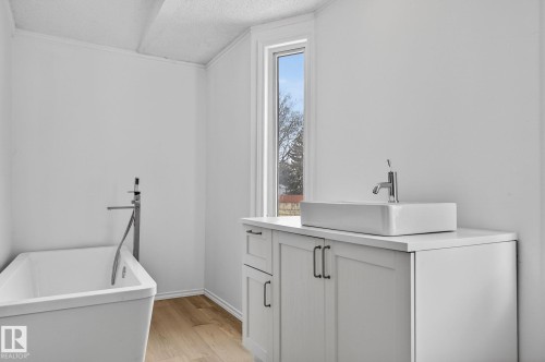 Laundry area with a textured ceiling, light wood-type flooring, and crown molding - 72 Evergreen Park, Edmonton, AB - Indoor Photo Showing Laundry Room