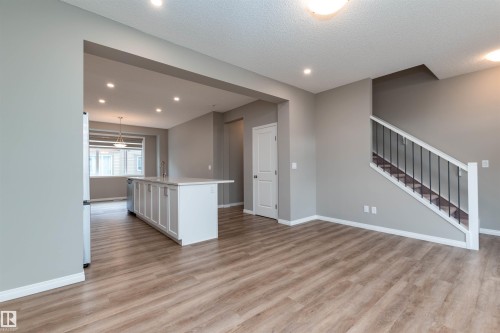 Unfurnished living room featuring light wood-style floors, stairway, recessed lighting, and a textured ceiling - 105 2072 Wonnacott Way, Edmonton, AB - Indoor Photo Showing Other Room