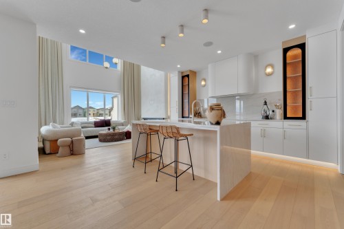 Kitchen with modern cabinets, white cabinets, light stone countertops, a center island with sink, and a breakfast bar area - 2408 1 Ave Sw, Edmonton, AB - Indoor Photo Showing Kitchen