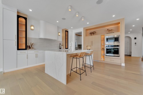 Kitchen with arched walkways, a kitchen breakfast bar, stainless steel appliances, modern cabinets, and light stone counters - 2408 1 Ave Sw, Edmonton, AB - Indoor Photo Showing Kitchen With Upgraded Kitchen