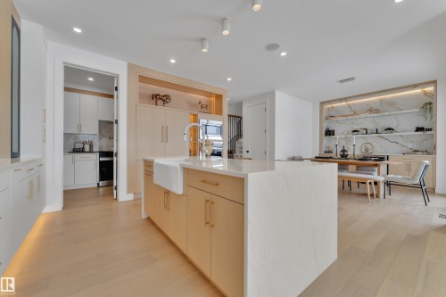 Kitchen with dual tone cabinetry, a center island with sink, light wood-type flooring, light stone countertops, and recessed lighting - 2408 1 Ave Sw, Edmonton, AB - Indoor Photo Showing Kitchen