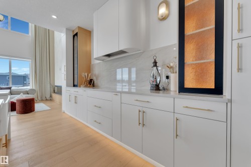 Bar with white cabinetry, light wood-style flooring, light stone counters, backsplash, and modern cabinets - 2408 1 Ave Sw, Edmonton, AB - Indoor
