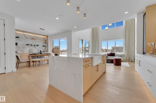 Kitchen featuring light wood finished floors, light stone counters, open floor plan, a center island, and hanging light fixtures - 2408 1 Ave Sw, Edmonton, AB - Indoor Photo Showing Kitchen