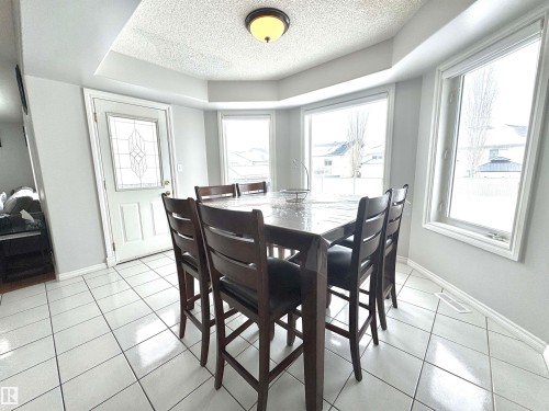 Dining room featuring light tile patterned floors, a textured ceiling, and a raised ceiling - 6734 162A Avenue, Edmonton, AB - Indoor Photo Showing Dining Room