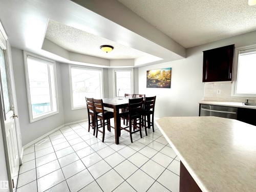 Dining space featuring a textured ceiling, light tile patterned floors, and a raised ceiling - 6734 162A Avenue, Edmonton, AB - Indoor Photo Showing Dining Room