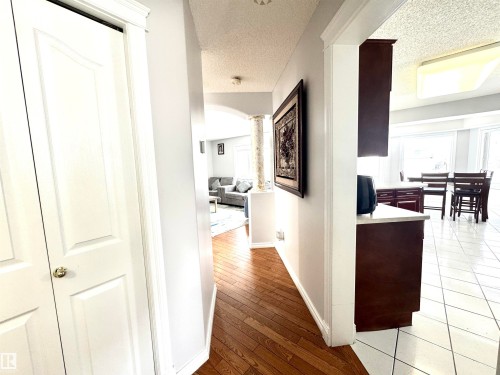 Hall with a textured ceiling, arched walkways, light wood-style floors, plenty of natural light, and ornate columns - 6734 162A Avenue, Edmonton, AB - Indoor Photo Showing Other Room