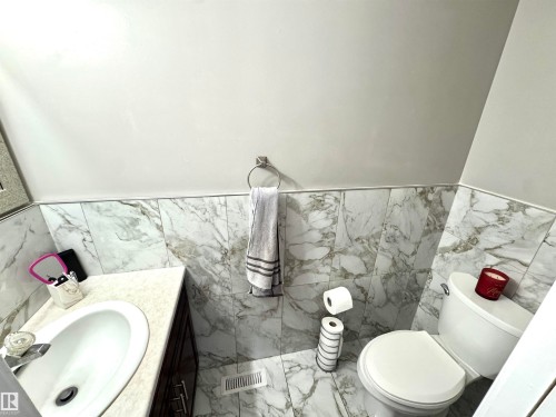 Half bath with vanity, a wainscoted wall, tile walls, and light marble finish floors - 6734 162A Avenue, Edmonton, AB - Indoor Photo Showing Bathroom