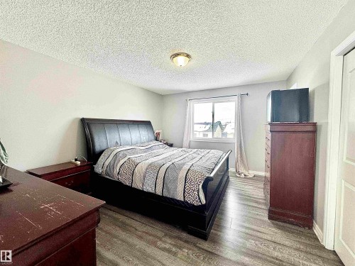 Bedroom featuring a textured ceiling and dark wood-style floors - 6734 162A Avenue, Edmonton, AB - Indoor Photo Showing Bedroom