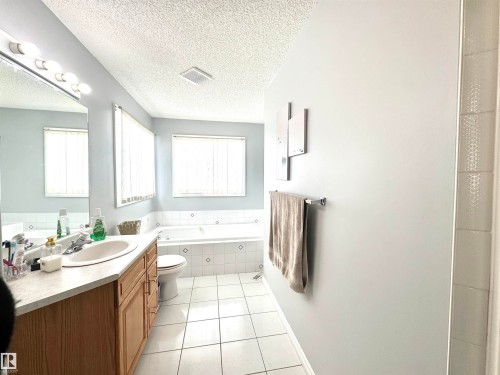 Bathroom with vanity, a bath, light tile patterned floors, and a textured ceiling - 6734 162A Avenue, Edmonton, AB - Indoor Photo Showing Bathroom