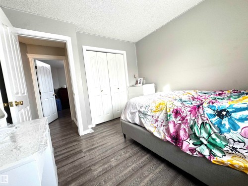 Bedroom featuring a textured ceiling, dark wood finished floors, and a closet - 6734 162A Avenue, Edmonton, AB - Indoor Photo Showing Bedroom