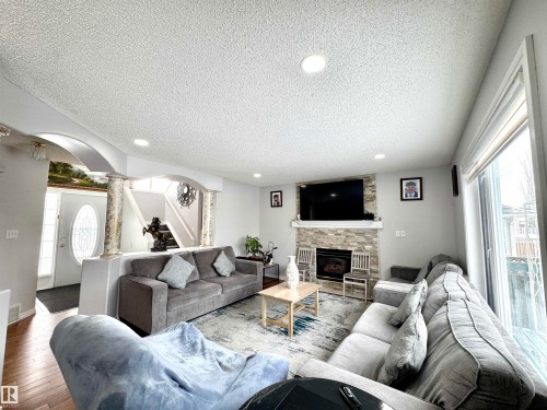 Living room with arched walkways, a textured ceiling, recessed lighting, hardwood / wood-style floors, and a fireplace - 6734 162A Avenue, Edmonton, AB - Indoor Photo Showing Living Room With Fireplace