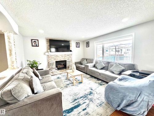 Living room featuring a fireplace, recessed lighting, a textured ceiling, and wood finished floors - 6734 162A Avenue, Edmonton, AB - Indoor Photo Showing Living Room With Fireplace