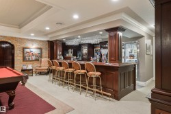 Community bar area featuring ornamental molding, billiards, dark wood finish cabinets, and dark countertops - 