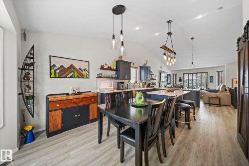 Dining space with a barn door, light wood-style flooring, and lofted ceiling - 103 Adams Close, Red Deer, AB - Indoor Photo Showing Dining Room