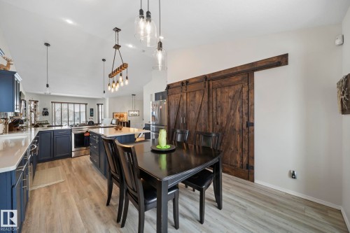 Dining space with a barn door, light wood-style floors, and vaulted ceiling - 103 Adams Close, Red Deer, AB - Indoor