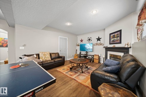 Living room with a glass covered fireplace, dark wood-type flooring, and a textured ceiling - 103 Adams Close, Red Deer, AB - Indoor Photo Showing Living Room With Fireplace