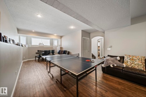 Playroom with arched walkways, dark wood-style flooring, a textured ceiling, and recessed lighting - 103 Adams Close, Red Deer, AB - Indoor