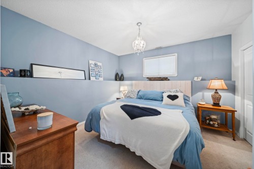 Bedroom with carpet flooring, a chandelier, and a textured ceiling - 103 Adams Close, Red Deer, AB - Indoor Photo Showing Bedroom